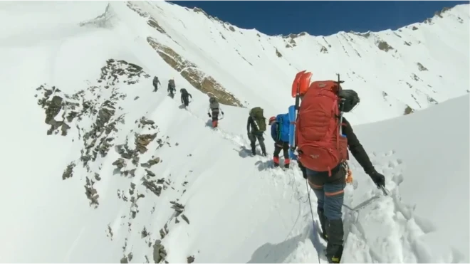 ఒక శిఖరాన్ని ఎక్కుతున్న పర్వతారోహక బృందం (వీడియోలోని చిత్రం)
