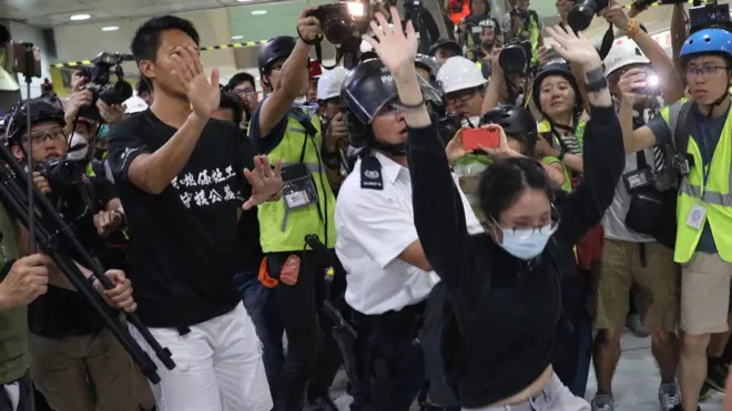 Seorang demonstran perempuan ditangkap polisi di Shatin, Hong Kong, pada Minggu (14/07).