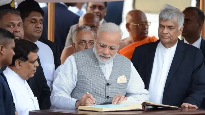 India's Prime Minister Narendra Modi (C) is watched by Sri Lankan Prime Minister Ranil Wickremesinghe (R) and other officials after signing the 'Golden Book' after arriving at Bandaranaike International Airport in Colombo on May 11, 2017, for a visit to Sri Lanka. / AFP PHOTO / LAKRUWAN WANNIARACHCHI (Photo credit should read LAKRUWAN WANNIARACHCHI/AFP/Getty Images