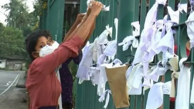 ২০ দিনের একটি মুসলিম শিশুকে জোর করে দাহ করার প্রতিবাদে কলম্বোর একটি ক্রিমেটোরিয়ামের দেয়ালে সাদা ফিতে ঝোলাচ্ছেন এক নারী