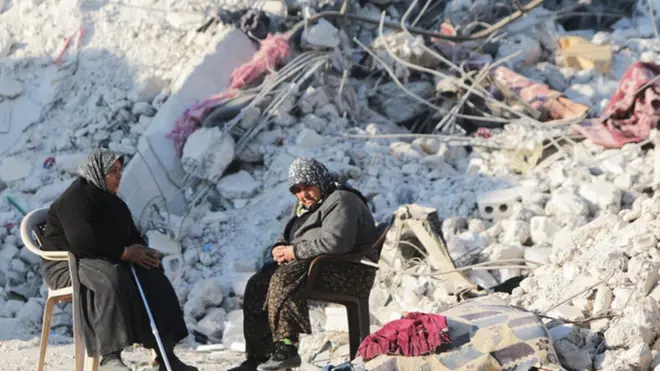 सीरिया के जिंदायर्स इलाक़े में एक ध्वस्त मकान के बाहर बैठी महिलाएं