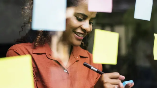 A woman writes on a post it note