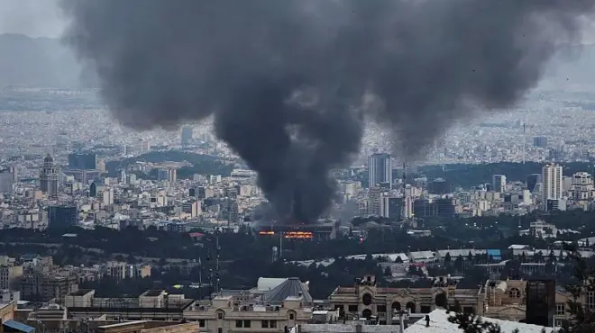 Asap membumbung setelah serangan Israel yang dilaporkan terhadap sebuah gedung yang digunakan oleh Jaringan Berita Republik Islam Iran, bagian dari stasiun TV pemerintah Iran, di Teheran, Iran pada 16 Juni 2025 