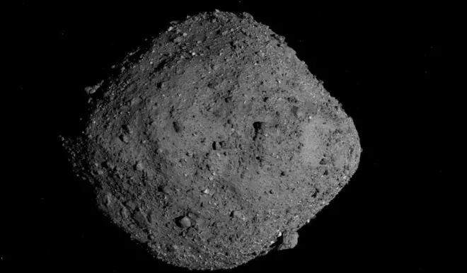 صورة لكويكب يبلغ عرضه 500 متر يسمى بينو، يشبه صخرة رمادية اللون، وهي أوسع في المنتصف منها في كل طرف. إنها ليست ناعمة - هناك كتل متعرجة مختلفة الحجم تخرج من سطحها.
