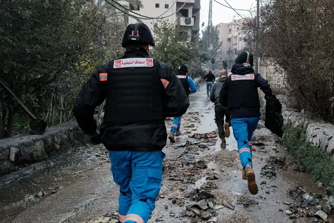 sırtı dönük halde çamurlu bir yolda koşan acil müdahale ekipleri