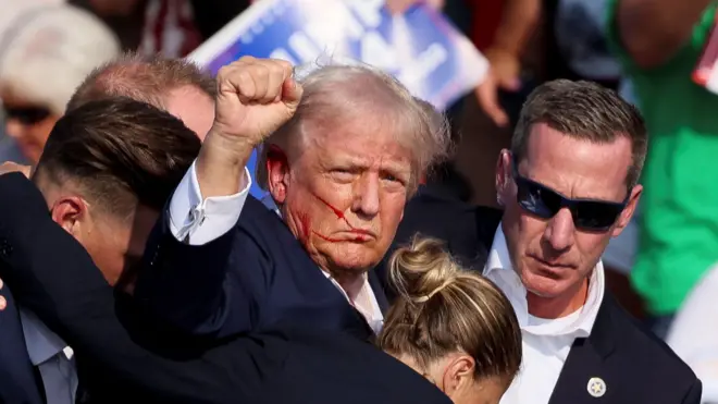 ပစ်ခတ်ခံရမှုအပြီး စင်ပေါ်ကနေ ဆင်းသွားတဲ့မစ္စတာ ထရမ့်ကို လုံခြုံရေးအဖွဲ့တွေနဲ့အတူ မြင်တွေ့ရတာဖြစ်ပါတယ် 