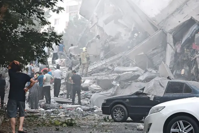 Varias personas observan los daños causados en edificios de la plaza Nobonyad tras los ataques aéreos israelíes el 13 de junio de 2025 en Teherán, Irán. 
