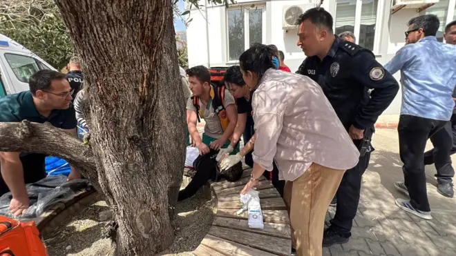 Okupljeni ljudi ispred škole ukazuju pomoć povređenom učeniku