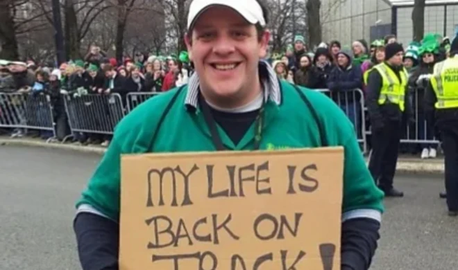 男性が「人生を立て直した」と書かれたプラカードを持っている