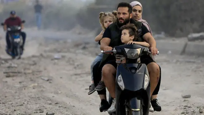 Gazze'de bir aileden dört kişi yıkıntılar arasında motorla ilerliyor