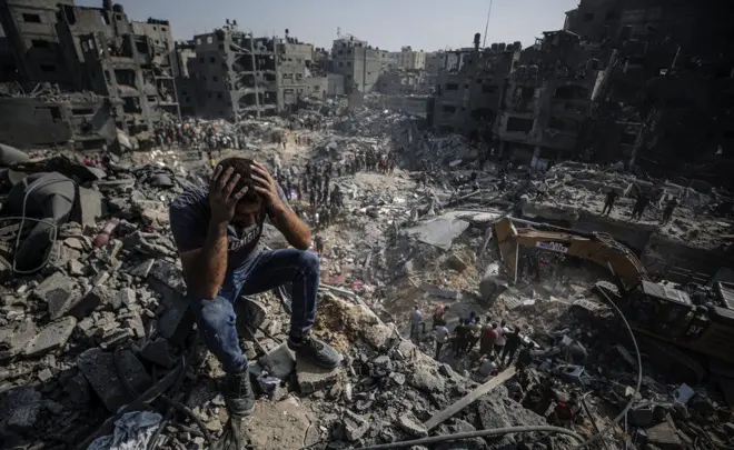 A man, sitting on debris, clutches his head as Palestinians conduct a search and rescue operation after the second bombardment of the Israeli army in the last 24 hours at Jabalia refugee camp in Gaza City, on 1 November 2023