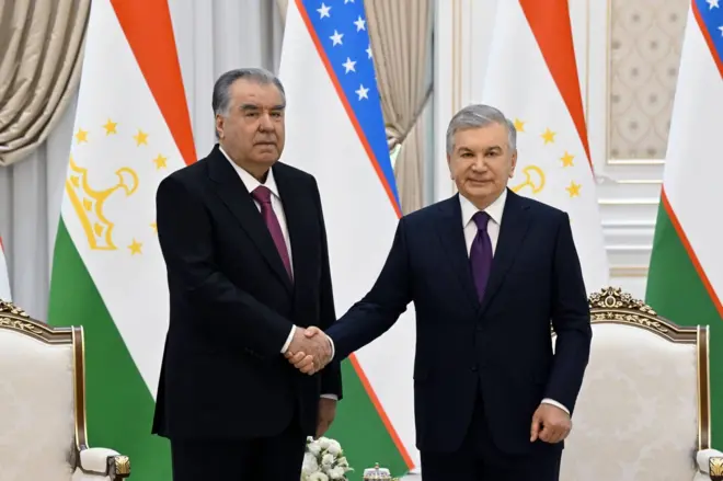Emomali Rahmon va Shavkat Mirziyoyev ikki davlat bayroqlari yonida.
