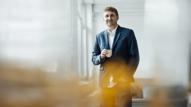 homem segura xícara de café em escritório 