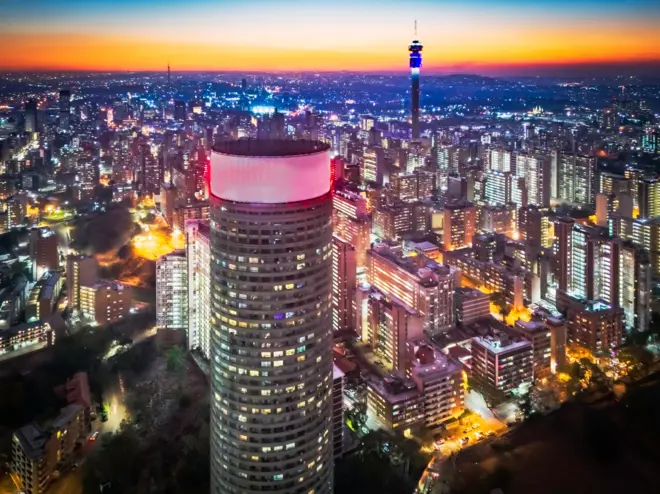 Hillbrow et Johannesburg le soir avec le soleil se couchant sur la tour de communication de Telkom vue des appartements de Ponte City. Johannesburg, également connue sous les noms de Jozi, Jo'burg ou eGoli, est la plus grande ville d'Afrique du Sud.