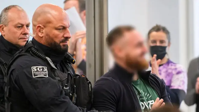 Обвиняемого Йоханна Г. доставляют в зал суда в начале процесса против семи левых экстремистов, обвиняемых в участии в преступной организации, 25 ноября 2025 года