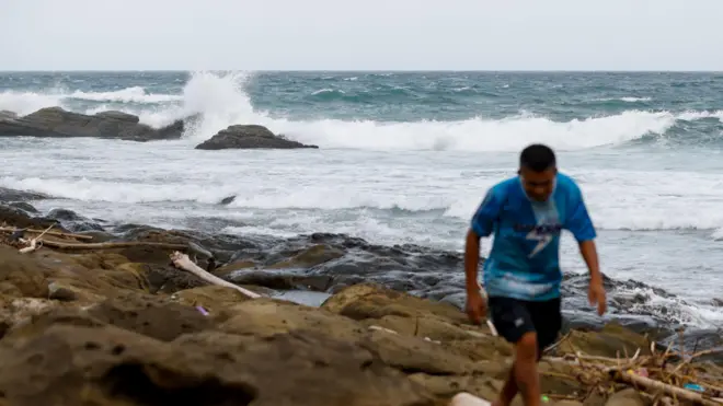 台灣新北一處海岸超強颱風樺加沙掀起的巨浪拍打岸邊岩石，一位路人走開（22/9/2025）