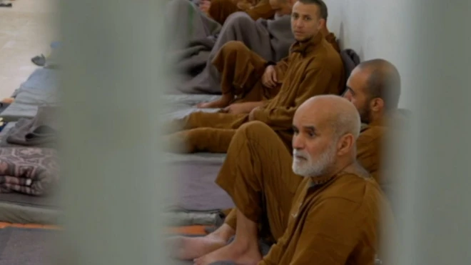 چند زندانی با لباس نارنجی در سلول عمومی