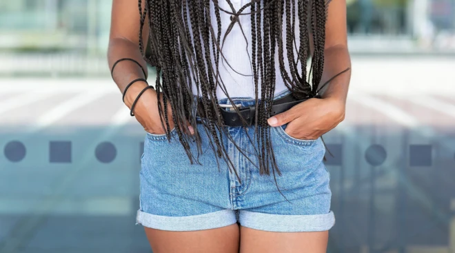 한 여성이 짧은 청바지 주머니에 손을 넣고 있다.