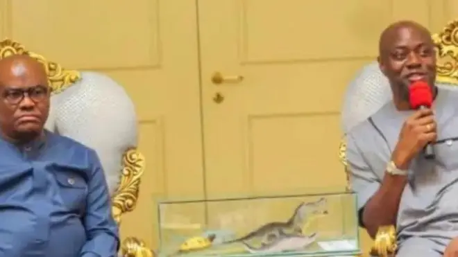 Aworan Minisita fun olu ilu ilẹ wa, Nyesom Wike, o wọ aṣọ alawọ aro, o si lo igo, o n wo ọọkan. Lẹgbẹẹ rẹ ni Gomina ipinle Oyo, Onimọẹrọ Seyi Makinde. Makinde mu ẹrọ gbohungbohun dani, o n sọrọ lọwọ , aṣo alawọ eeru lo wọ, o si n rẹrin-in muse. IlẹKun alawọ ofeefe ni aworan to wa lẹyin wọn.