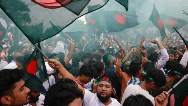 バングラデシュの、緑に赤い丸の描かれた国旗を振り回す群衆。大勢が国旗をあしあらった鉢巻を巻いている
