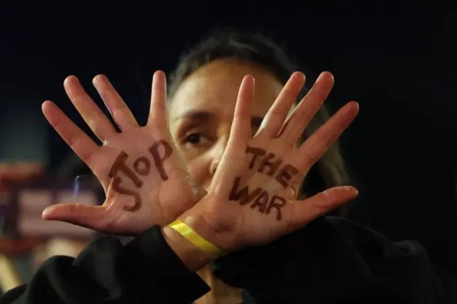 شخص يرفع يديه مكتوباً عليهما "أوقفوا الحرب".