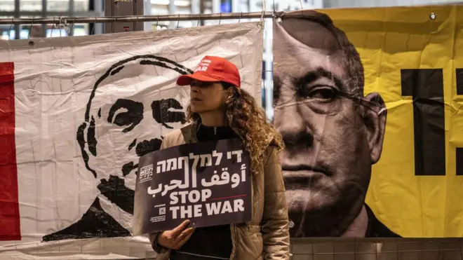 متظاهرة أمام صورة لنتنياهو في إطار احتجاجات إسرائيلية لحث الحكومة الإسرائيلية على توقيع اتفاق وقف إطلاق النار مع غزة في 4 يناير/كانون الثاني 2025