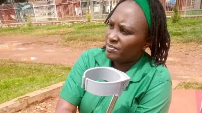 Umumenyeshamakuru Sandra Aline Muhoza yicaye yambaye umwambaro w'urwatsi rutoto w'abanyororo mu Burundi imbere yiwe hari imbago