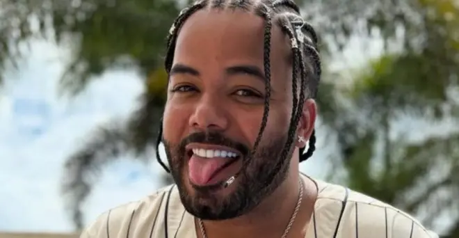 Hytalo Santos sorrindo para a foto, com língua para fora, em ambiente externo com árvores