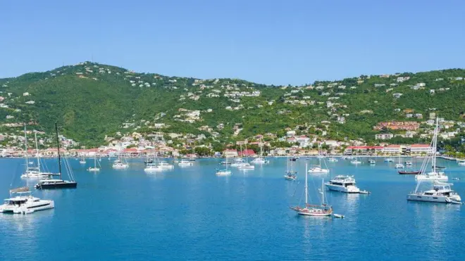 مراكب بيضاء على صفحة مياه زرقاء، في حضن تلال خضراء مرصّعة بمبان بيضاء اللون، في جزيرة سانت توماس