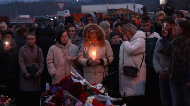 Personas lloran frente a arreglos florales colocados en el audotorio Crocus de Moscú