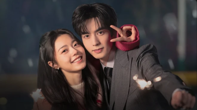 一对外表吸引的中国情侣对着镜头微笑。女子留着长发，将手臂环绕在男子肩膀上，并比出和平手势；男子身穿西装，手持一支点燃的仙女棒，朝向镜头