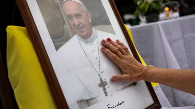 Pessoa coloca mão em quadro do papa Francisco