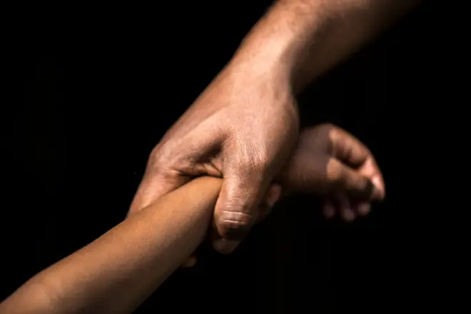 පුද්ගලයෙකු කුඩා දරුවෙකුගේ අතින් අදින අයුරු දැක්වෙන ඡායාරූපයකි