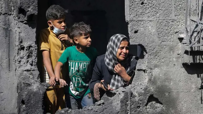 File photo showing Palestinian children looking out from their family's destroyed house following an Israeli air strike, in Shati refugee camp, northern Gaza (29 October 2025)