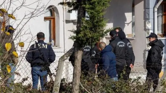 چند سرباز پولیس ترکیه با لباسهای سیاه در مقابل یک منزل ایستاده اند.