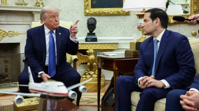 الرئيس الأمريكي دونالد ترامب يلوح بيده بينما ينظر إليه وزير الخارجية الأمريكي ماركو روبيو.