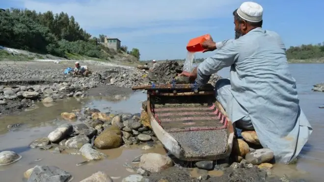 नदी से सोना निकालता शख़्स