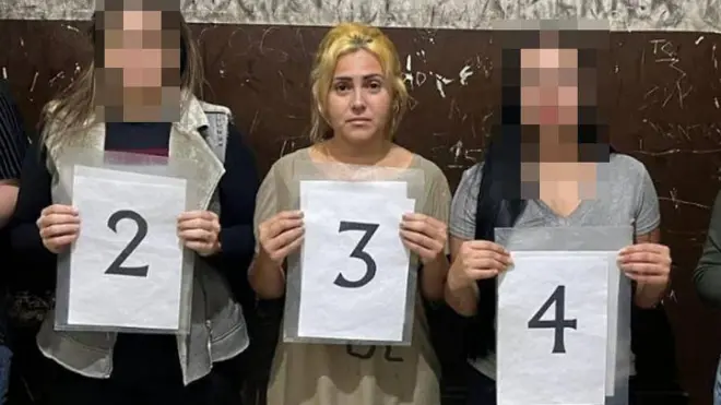 Ana Paula Veloso Fernandes segura placa "3" ao ser presa em Guarulhos
