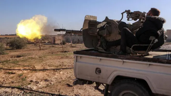 Arazi aracının arkasına yerleştirilmiş ağır bir silahı kullanan montlu bir erkek savaçının açtığı ateş havada bir alev topu oluşturmuş, Araç, bakir bir arazide park etmiş. 10 Ocak 2025