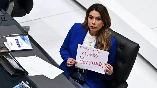 La diputada opositora de ARENA, Marcela Villatoro, con un cartel que dice "Hoy murió la democracia" durante una sesión plenaria del Congreso en San Salvador
