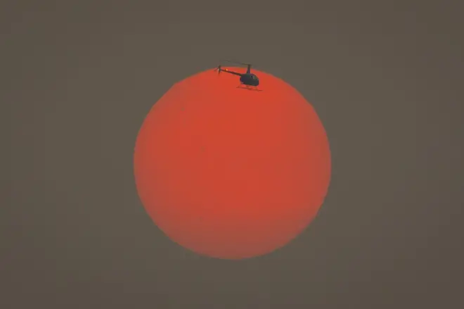 Um helicóptero voa através do sol alaranjado pela fumaça dos incêndioscomo ganhar na roleta do cassinoSão Paulo