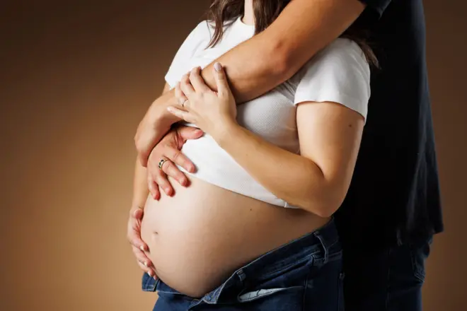 ගර්භණී කාන්තාවකගේ උදරය වටා අත තබාගෙන සිටින පිරිමි පුද්ගලයෙක්