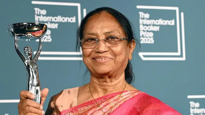 Banu Mushtaq dressed in a red sari poses with her trophy at the Tate Modern on May 20, 2025 in London, England.