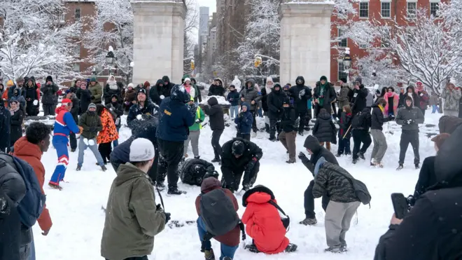 Dezenas de pessoas brincam e atiram bolas de neve no Washington Square Park, em Nova York