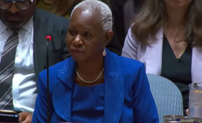 Bintou Keita yambaye ikoti n'ikanzu bisa vy'ubururu, afise imvi akaba yambaye n'umugufu ukayangana mw'izozi n'ihereni ariko avuga ataraba camera na micro, hari abandi bantu baboneka inyuma yiwe 