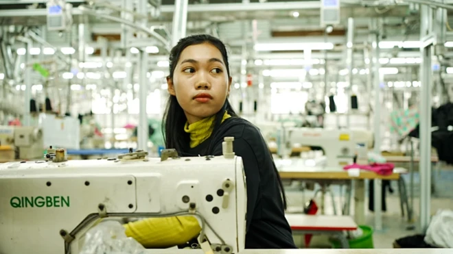 عاملة أمام ماكينة خياطة في مصنع