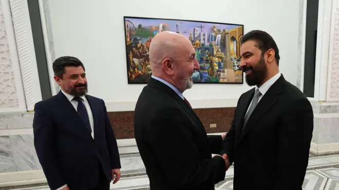 الصورة تظهر الرئيس العراقي وهو يصافح السيد علي الزيدي رئيس الوزراء الجديد مستقبلا إياه ليكلفه برئاسة الوزارة بينما ينظر أحد المرافقين من الخلف 