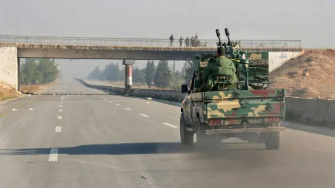 Forças rebeldes dirigindo por uma rodovia na Síria