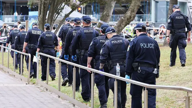 Группа полицейских в синей форме идет по газону вдоль мощеной плиткой дорожки