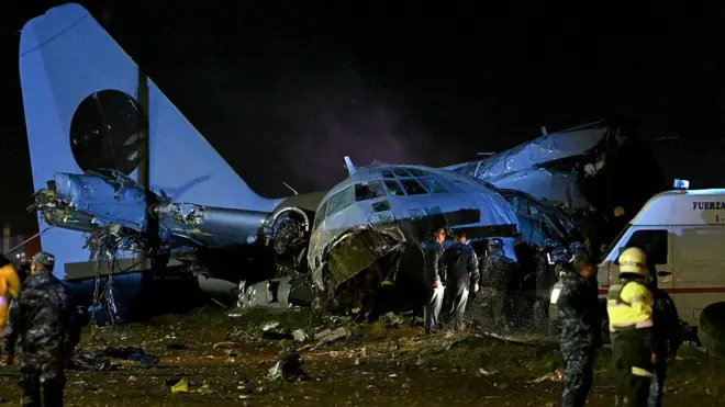 обломки самолета лежат на земле, рядом ходят спасатели